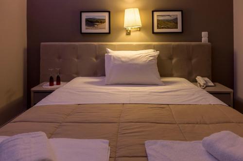 a bedroom with a large bed with a lamp and a phone at Apollon Hotel in Ancient Epidavros