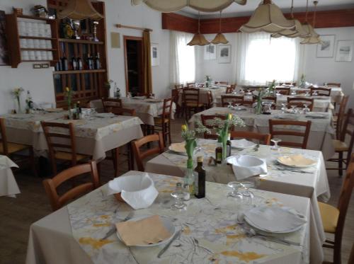 uma sala de jantar com mesas e cadeiras com toalhas de mesa brancas em Verda Val em Campitello di Fassa