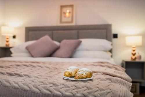 a bed with two croissants and a plate of bread at INFINITY CENTAR Zagreb in Zagreb