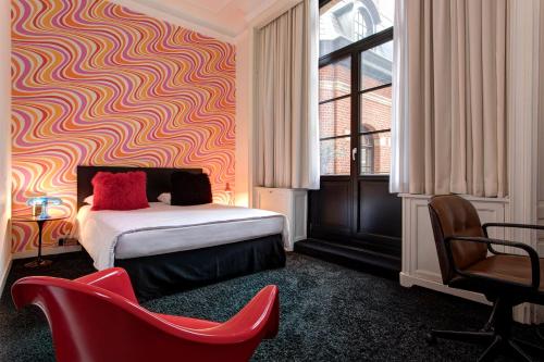 
a room with a bed, chair, lamp and window at Vintage Hotel Brussels in Brussels
