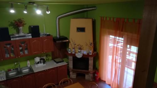 a kitchen with red cabinets and a fireplace in a room at Vár-Liget Vendégház in Kisnána