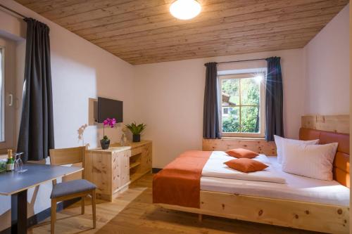 a bedroom with a bed and a desk and a window at Refugium Dolomiten & Chalet in Sillian