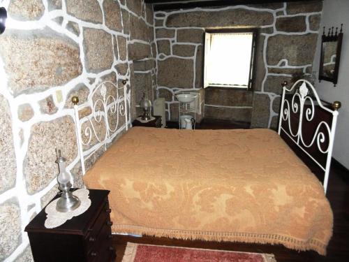 a bedroom with a bed and a stone wall at Casa do Brigadeiro in Lajeosa