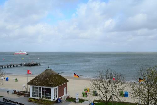 a building on the beach with a boat in the water at Kurhaus Hotel in Wyk auf Föhr