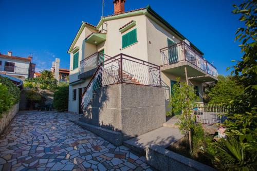 une maison blanche avec balcon dans une rue pavée dans l'établissement Villa Vosilla Apartments, à Cres