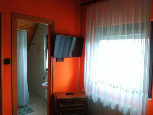a bathroom with a tv on the wall and a window at Napfény villa in Balatonfüred