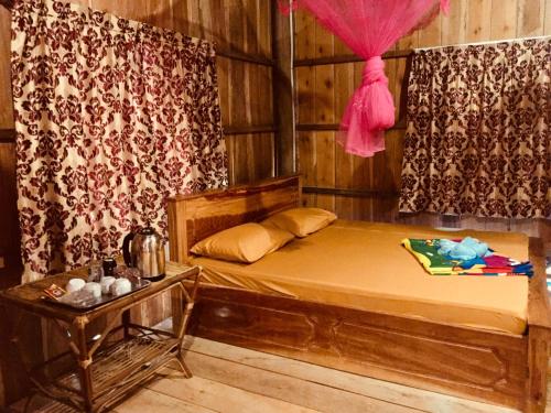 瓜隆岛PSK VIMEAN KOH RONG Guesthouse的一间卧室配有一张带粉红色窗帘的木床
