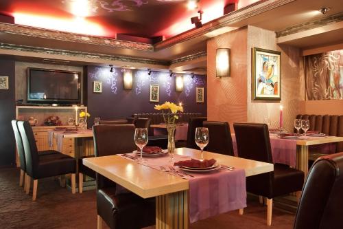 a dining room with tables and chairs and a television at Saint George Hotel & Medical Spa in Pomorie