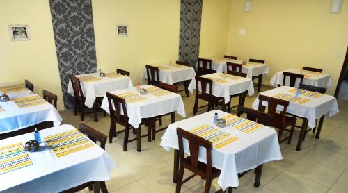 een eetkamer met tafels en stoelen met witte tafellakens bij Hotel Monte Carlo Uberlândia in Uberlândia