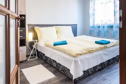 a bedroom with a bed with blue towels on it at Alma Apartman in Salgótarján