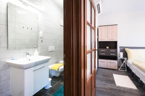 a bathroom with a sink and a toilet and a bed at Alma Apartman in Salgótarján