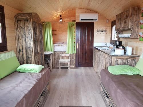 una habitación con 2 camas y una cocina en una cabaña en La roulotte de Chiroubles en Chiroubles