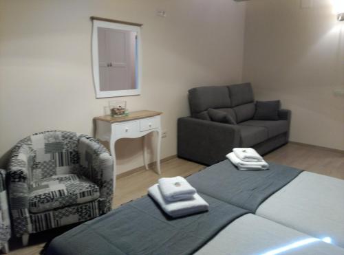 a bedroom with a bed and a couch and a chair at El Rincón del Gallo in Tronchón