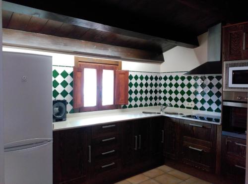 a kitchen with wooden cabinets and green and white tiles at El Rincón del Gallo in Tronchón