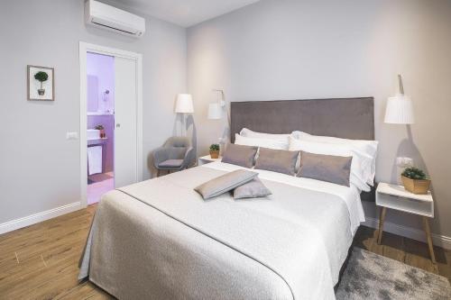 a white bedroom with a large bed and a chair at Colonna Luxury Suites in Rome