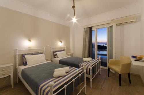 1 dormitorio con 2 camas, escritorio y ventana en Nikolas Hotel, en Parikia