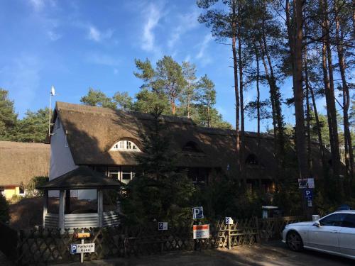 athatched house with a car parked in front of it at Ferienhaus Duenenwald 1 _LANG in Ostseebad Karlshagen