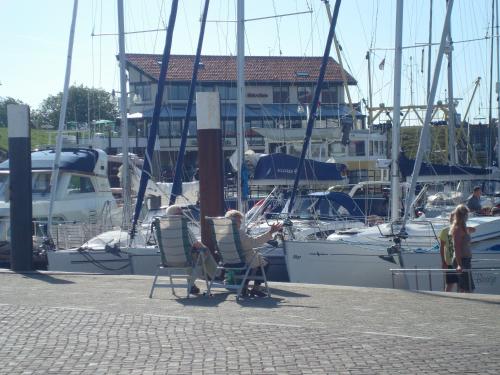 a couple of chairs sitting on a dock with boats at Hotel Havenzicht Texel in Oudeschild