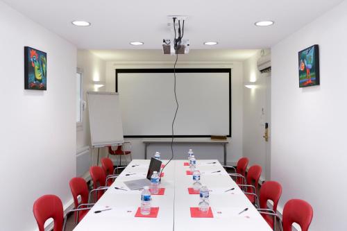 a conference room with a long table with red chairs at ibis Dole Sud Choisey in Dole