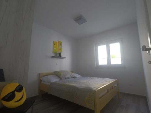 a white bedroom with a bed and a window at Apartment Lola in Srima