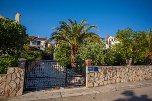 une porte avec un mur en pierre et des palmiers dans l'établissement Villa Vosilla Apartments, à Cres
