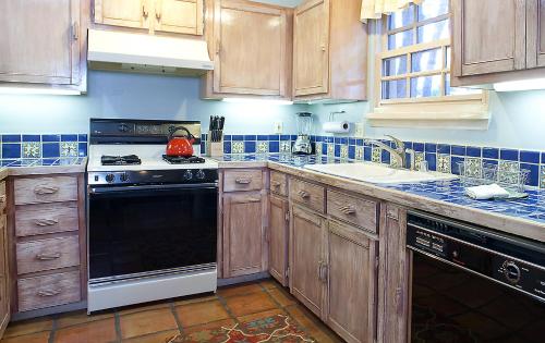 a kitchen with wooden cabinets and a black stove top oven at Casa de Tres Lunas/House of Three Moons in Santa Fe