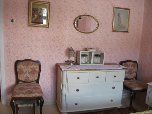 a room with a dresser and two chairs and a mirror at The Pink House in Polkownik Serafinowo