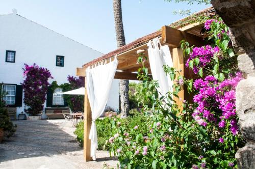 a garden with purple flowers and a wooden pergola at Hotel Rural Biniarroca - Adults Only in Sant Lluis