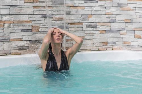 a woman in a swimming pool with her hands on her head at Hotel Donatello Imola in Imola