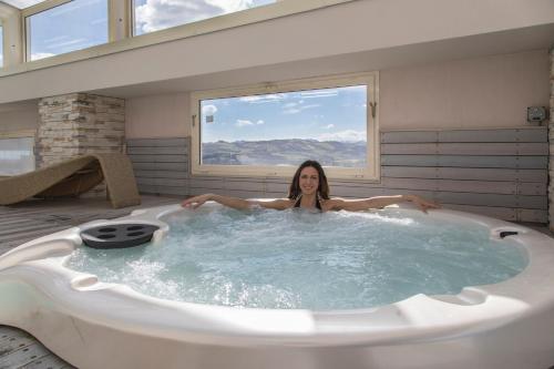 una donna in una vasca da bagno in una stanza con finestra di Hotel Donatello Imola a Imola