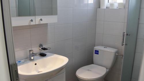 a white bathroom with a toilet and a sink at Hotel MK, Plavi restoran, Loznica in Loznica