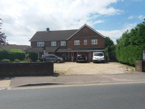 a house with two cars parked in front of it at Lynn Hill Guest House in East Dereham