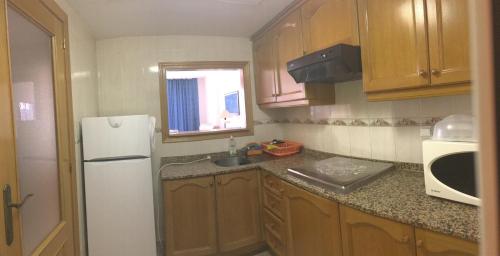 ビリャホヨサにあるConfradesの小さなキッチン(木製キャビネット、白い冷蔵庫付)