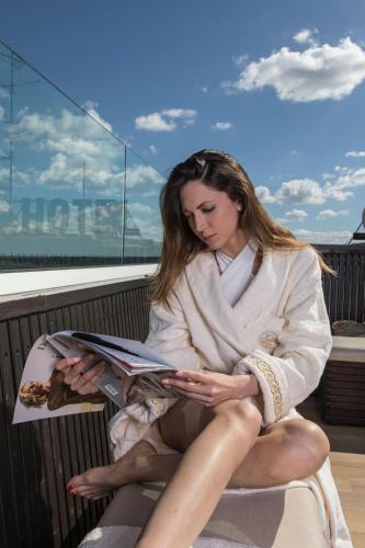 a woman sitting on a bench reading a magazine at Hotel Donatello Imola in Imola
