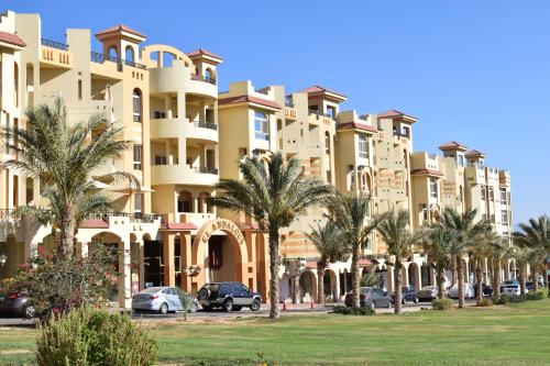 a large building with palm trees in front of it at 310 el Andalous Apartment in Hurghada