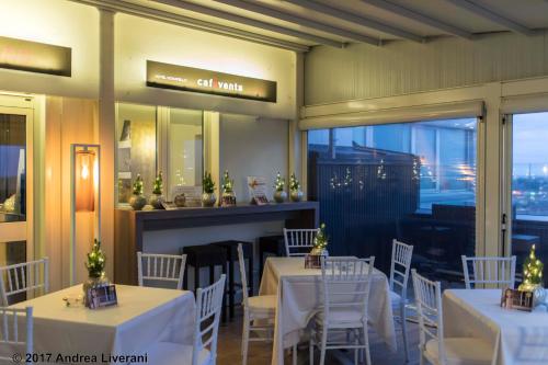 a restaurant with white tables and chairs and a window at Hotel Donatello Imola in Imola