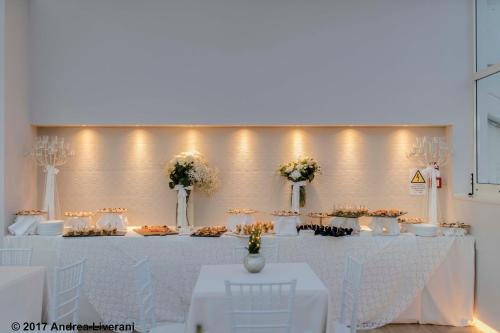a white table with white chairs and flowers on it at Hotel Donatello Imola in Imola