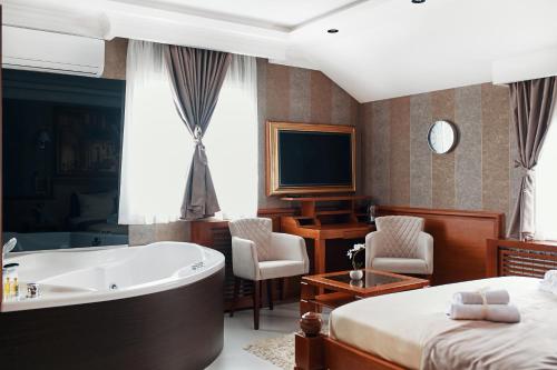 a bedroom with a tub and a bed and a television at Lux apartmani Beograd in Belgrade