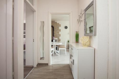a white hallway with a mirror and a white dresser at Royal View Apartment in Zadar