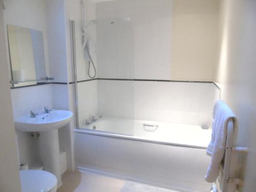 a white bathroom with a tub and a sink at Liverpool 2 Bedroom Apartment in Liverpool
