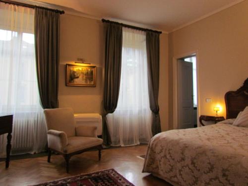 a bedroom with a bed and a chair and windows at L'Approdo di Sant'Agostino in Como