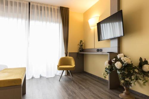 a hotel room with a tv and a yellow chair at Hotel Donatello Imola in Imola