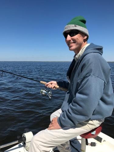 a man sitting on a boat holding a fishing rod at Steinhatchee River Inn and Marina in Steinhatchee