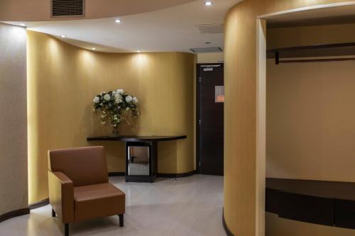 a waiting room with a chair and a table and flowers at Hotel Donatello Imola in Imola