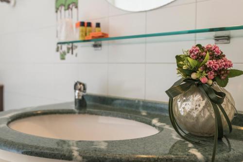 a bathroom sink with a vase with flowers in it at Hotel Donatello Imola in Imola