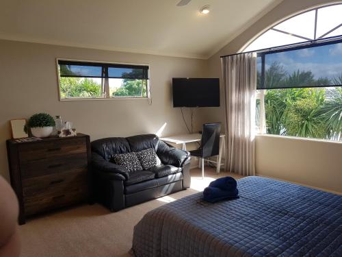 a bedroom with a bed and a couch and a chair at Makepeace Place Homestay in Hamilton