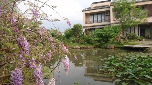 a garden with a pond in front of a building at Dragonfly B&B in Dazhou