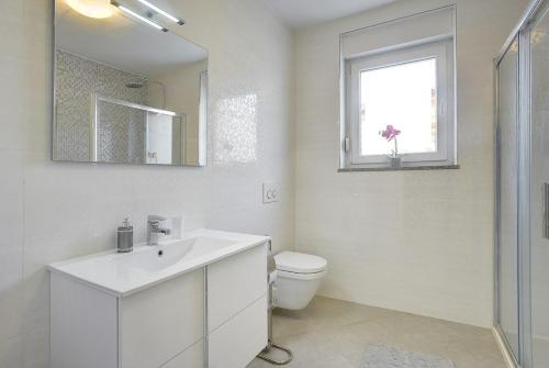 a white bathroom with a sink and a toilet at Villa Rudy in Štinjan