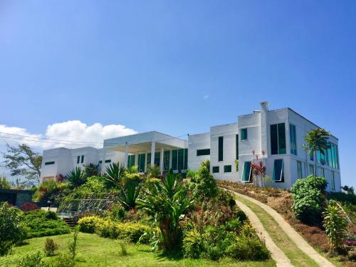 ヌワラエリヤにあるSingha Sanasa Luxury Homestayの緑の窓と庭のある白い家
