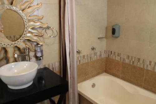 y baño con lavabo, bañera y espejo. en Hotel El Refugio, en Tlaxcala de Xicohténcatl